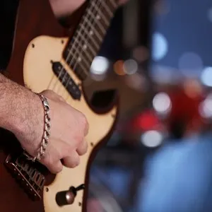 Young man playing on electric guitar close up