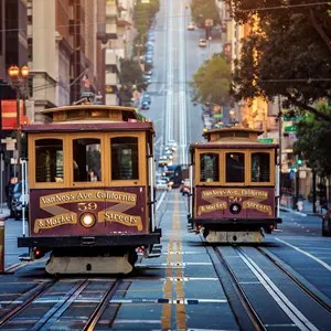 Classic view of historic traditional Cable Cars riding on famous California Street in morning light at sunrise with retro vintage style