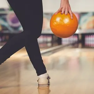 Young woman is playing bowling, preparing to throw ball