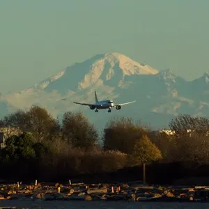 An airplane coming in to land at Vancouver airport with Mt. Baker in the background