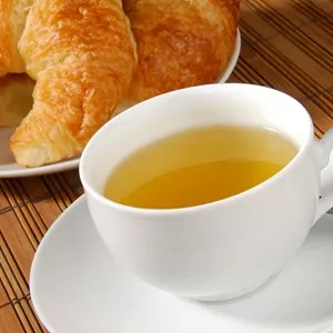A cup of green tea with fresh golden croissants