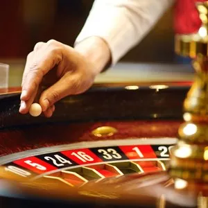 The croupier holds a roulette ball in a casino in his hand.