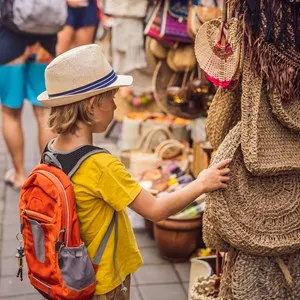 Boy at a market in Ubud, Bali. Typical souvenir shop selling souvenirs and handicrafts of Bali at the famous Ubud Market, Indonesia. Balinese market. Souvenirs of wood and crafts of local residents