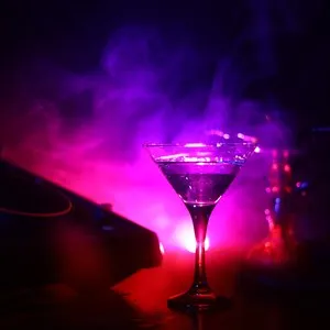 Glass with martini with olive inside on dj controller in night club
