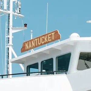 A white boat that has a wooden sign reading "Nantucket."