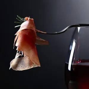 Prosciutto with rosemary and glass of red wine on datk background