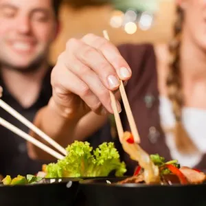 Young people eating with chopsticks in an Asian restaurant