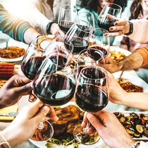 Happy friends toasting red wine glasses at dinner party - Group of people having lunch break at bar restaurant - Life style concept with guys and girls hanging out together - Food and beverage