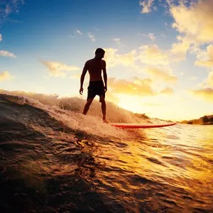 Young Man Riding Wave at Sunset