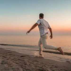 Man Running on Beach at Dusk under Clear Sky
