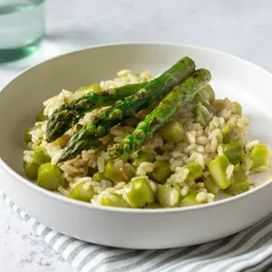 Delicious risotto with grilled green asparagus on white plate