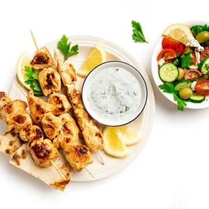Grilled souvlaki skewers, greek salad and tzatziki sauce on plate