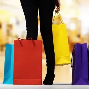 Young woman with shopping bags over shopping mall background with copy space. Shopping concept.