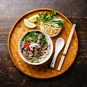 Pho Bo vietnamese Soup with beef on bamboo tray on wooden background