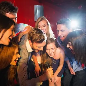 Happy friends singing karaoke together in a bar