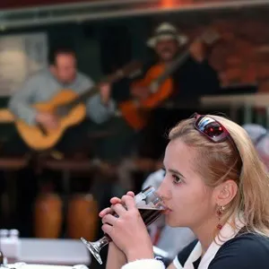 Girl drinking beer alone in a restaurant with live music
