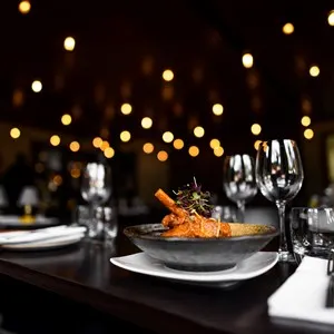 Elegant plated dish in a sophisticated restaurant setting with warm bokeh lighting in the background, highlighting the ambiance and fine dining experience.
