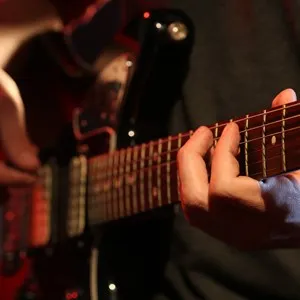 Young man playing on electric guitar close up