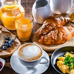 Breakfast served with coffee, orange juice, scrambled eggs, cereals, pancakes and croissants.