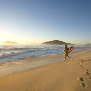 Surfer running into the surf at Bennetts Beach in Hawks Nest