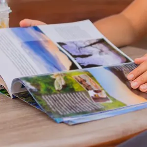 Female reading a magazine and drink ice coffee on wooden table.