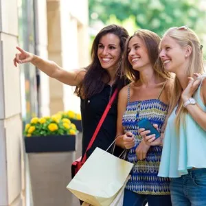 Outdoor portrait of group of beautiful girls looking at the shop window.
