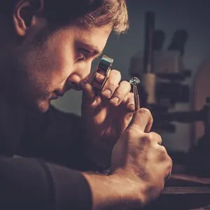 Jeweler looking at the ring through microscope in a workshop.