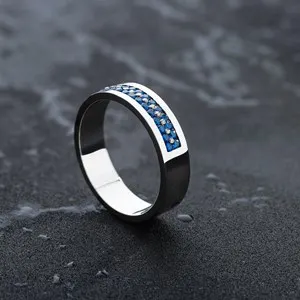 Silver ring with blue gemstones on black background. White gold wedding ring for men