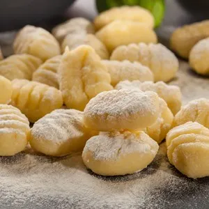 Uncooked homemade gnocchi on black cutting board