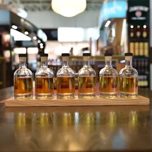 Small Test Alcohol bottles on table with reflection of the bottles on whiny wood top