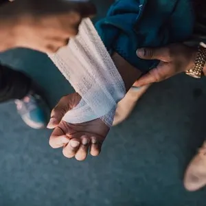 Person Putting Bandage on Another Person's Hand