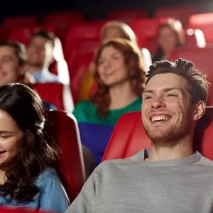 cinema, entertainment and people concept - happy friends watching comedy movie in theater