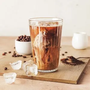 Wooden board with glass of cold brew and coffee beans on beige table