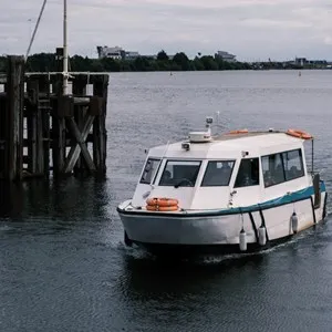 water bus floats by a wooden bollard in Cardiff Bay, Wales