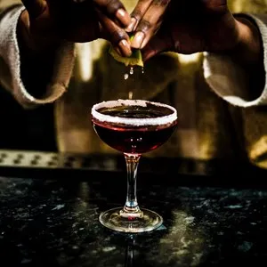 squeezing a lime over a cocktail in a dim speakeasy, Alchemist Bar & Lounge, San Francisco, California