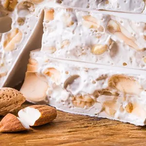 Torrone or nougat with nuts on wood background.