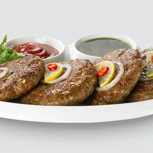 Spicy Pakistan Chapli Kebabs with fresh vegetables close up in the plate on the table.