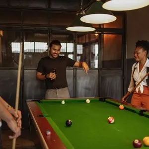 three people playing billiards at a bar