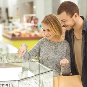 Online shopping. Beautiful young woman showing something on her smart phone to her handsome boyfriend while shopping together at the mall consumerism online shopping technology relationship concept