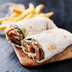 greek gyro wrap cut in half and served with fries