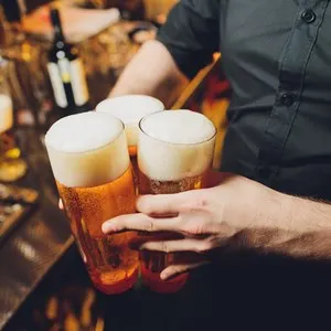 Waiter serving glasses of cold beer on the tray.
