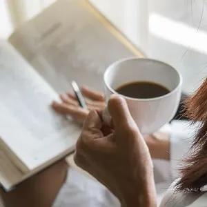 Woman Holding a Cup pf Coffee and a Book