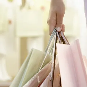 Detail close up of a woman's hand holding shopping bags by fashion store.