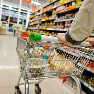 A Shopper Pushes a Trolley along a Supermarket Aisle.