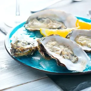 Fresh Oysters close-up on blue plates, served table with oysters, lemon and ice. Healthy sea food. Fresh Oyster dinner in restaurant. Gourmet food. - Picture