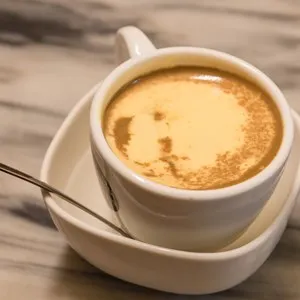Top view a cup of Giang egg coffee in Hanoi on marble table. Since 1946 the coffee is dripped and brewed in a small cup with filter then addition of well-whisked mixture yolks and other ingredients.