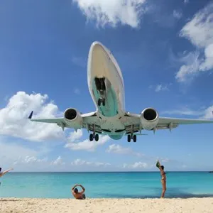plane landing over Maho beach, people posing