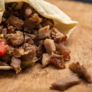 Doner kebab is on the cutting board. Shawarma with meat, onions, lettuce lies on a black background.