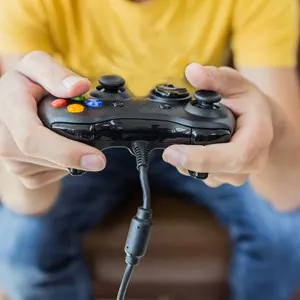 An Asian young man holding game controller playing video games