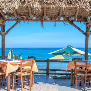 Beach cafe with wooden tables and chairs placed at the sea waterfront
